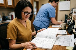A veterinary practice owner sketching a three-year plan across a large sheet at her desk beside a printed trend chart.