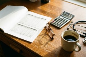 A printed valuation multiples comparison on a veterinarian's desk beside a calculator, reading glasses and a stethoscope.